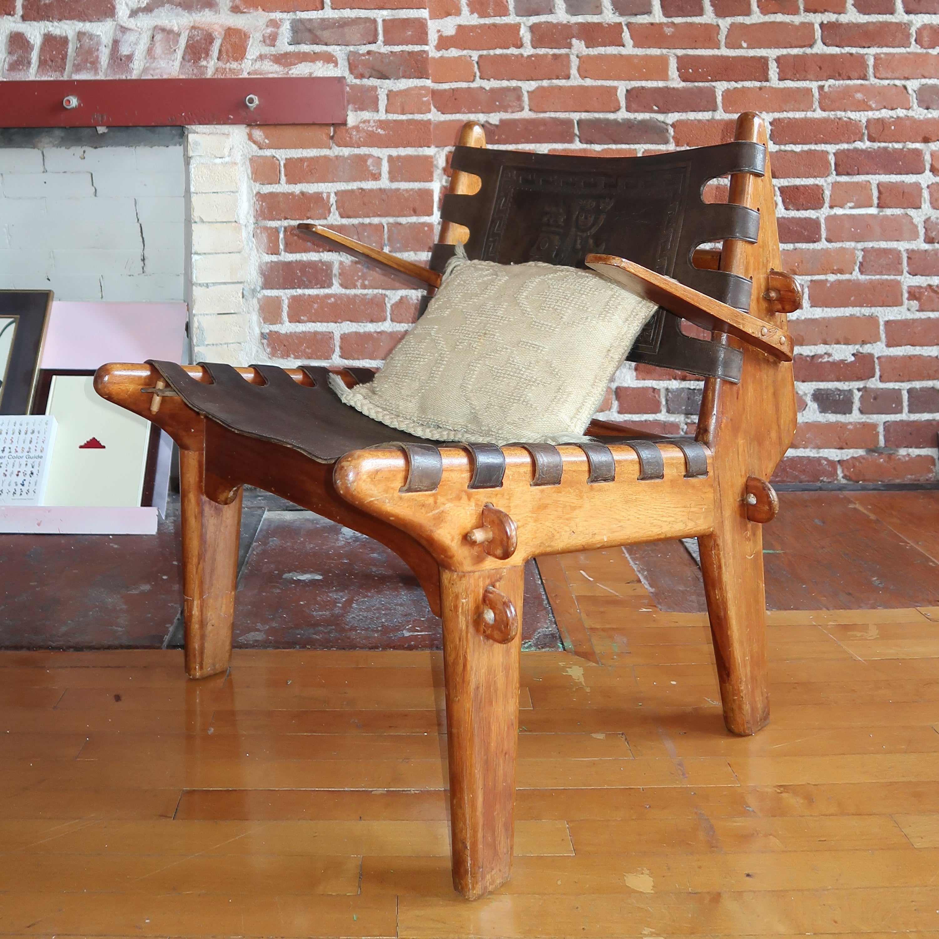 Wooden chair with a cushion against a brick wall.