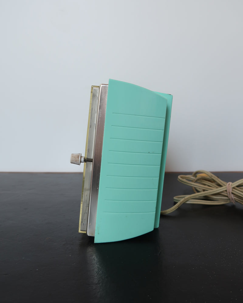 Mid-century turquoise GE Telechron wall clock with white numerals, day-date window, and electric plug-in design.
