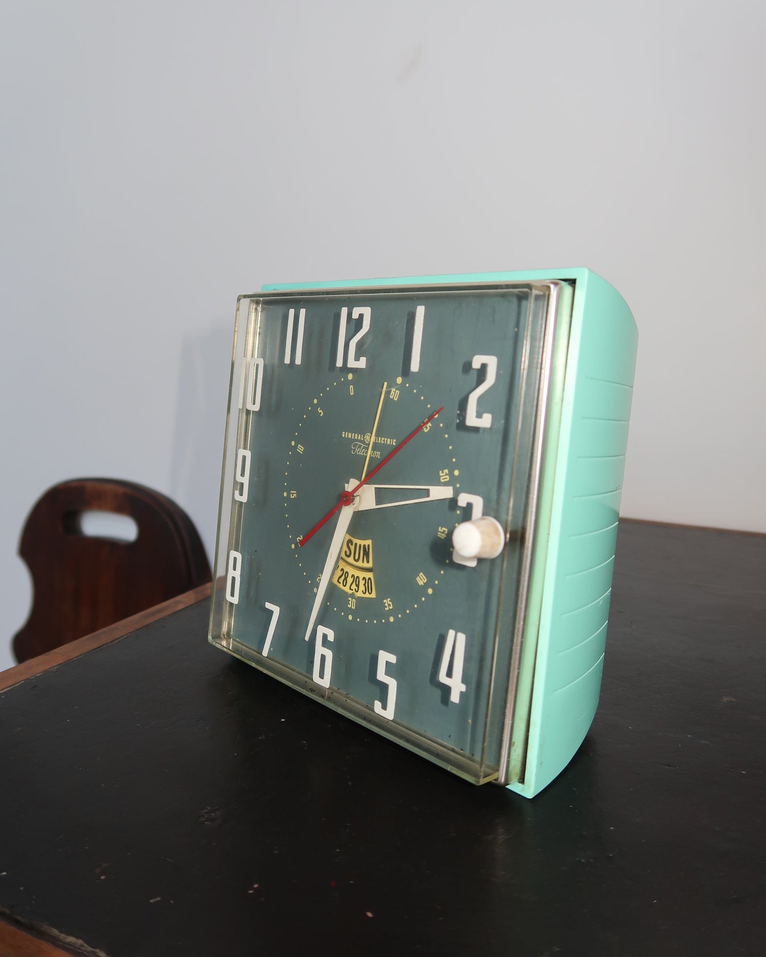 Mid-century turquoise GE Telechron wall clock with white numerals, day-date window, and electric plug-in design.